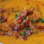 Creamy butternut squash soup with a swirl of cream and fresh herbs in a bowl