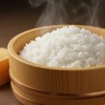 Steamed sushi rice in wooden bowl with rice paddle