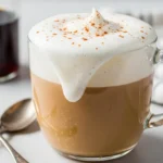 Homemade latte chai in a glass mug topped with cinnamon