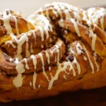 Freshly baked cinnamon roll pumpkin bread with cream cheese glaze dripping over the sides.