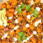 Ground beef and sweet potato skillet with fresh herbs served in a cast iron pan.