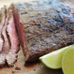 Raw flank steak with spices and marinade ingredients on a cutting board