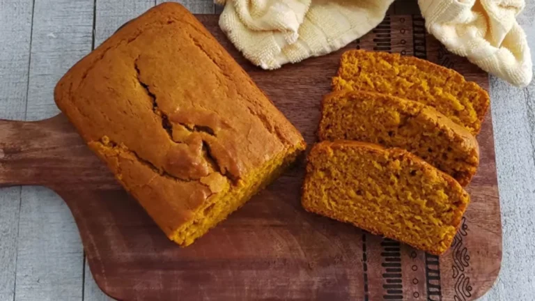 Easy Pumpkin Bread Recipe –Moist and Full of Fall Flavor 10 Freshly baked homemade pumpkin bread sliced on a wooden board.