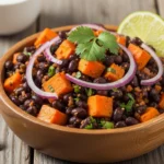 Overhead shot of roasted sweet potato black bean salad with corn, red onion, and cilantro in a white serving bowl.