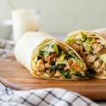 Crispy chicken nugget wrap sliced in half on plate with ranch drizzle.