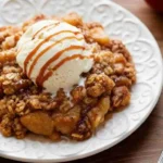Homemade apple crisp with golden oat topping served with ice cream.