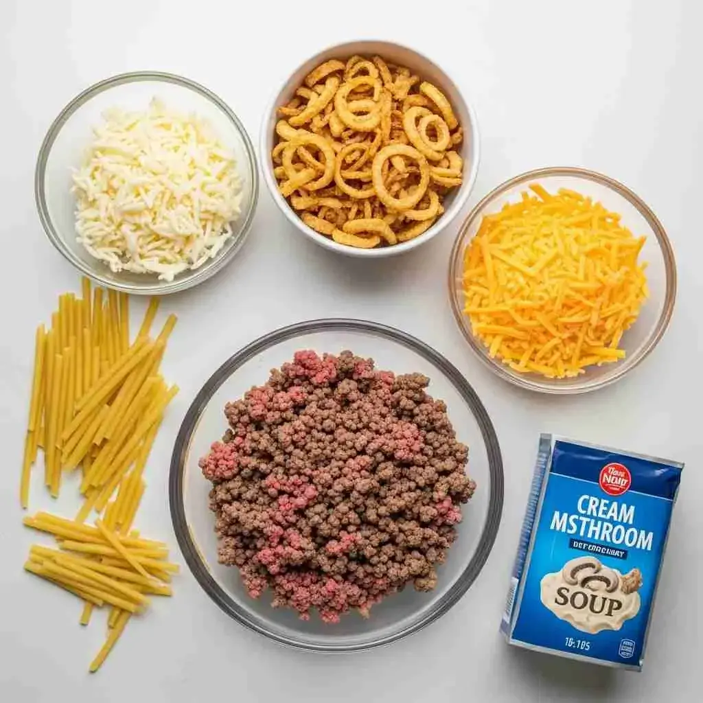 Cheesy Beef and Noodle Casserole with Crispy French Onions 2 Ground beef, egg noodles, cheese, cream sauce, and crispy French onions on countertop.