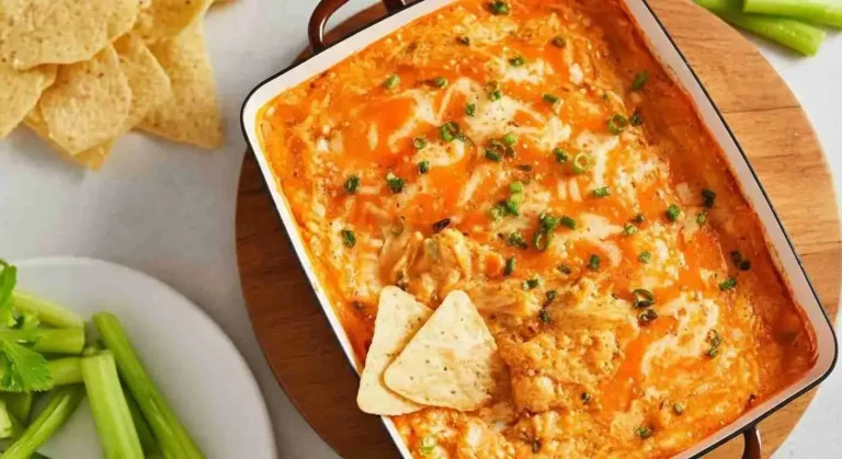 Baked buffalo chicken dip in a skillet topped with melted cheese and green onions