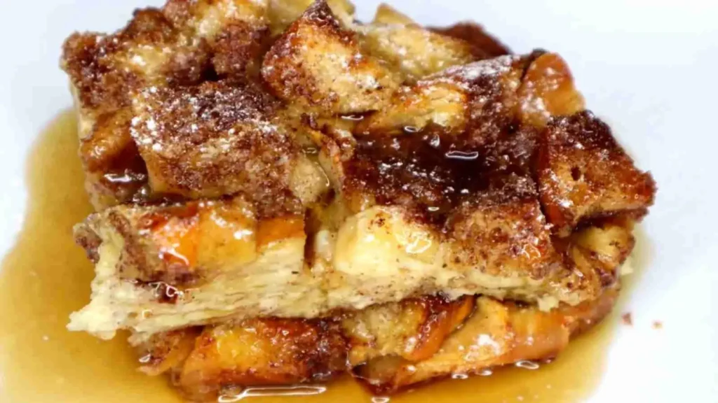Slice of caramel apple stuffed French toast casserole on a plate with extra caramel sauce.