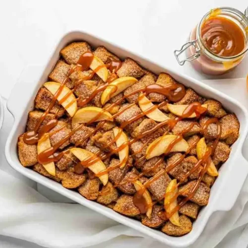 Caramel apple stuffed French toast casserole topped with caramel drizzle and apples