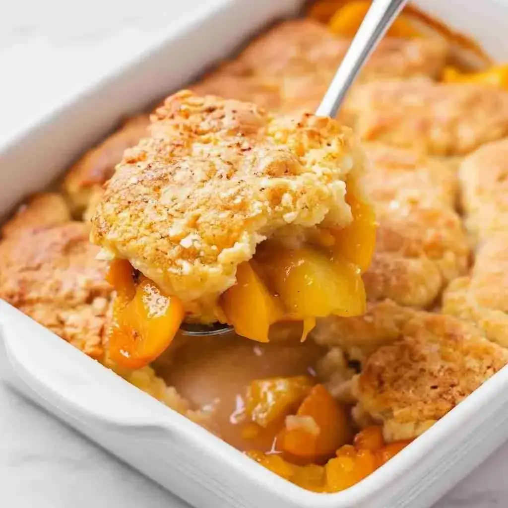 Close-up of golden crust and juicy canned peaches in peach cobbler