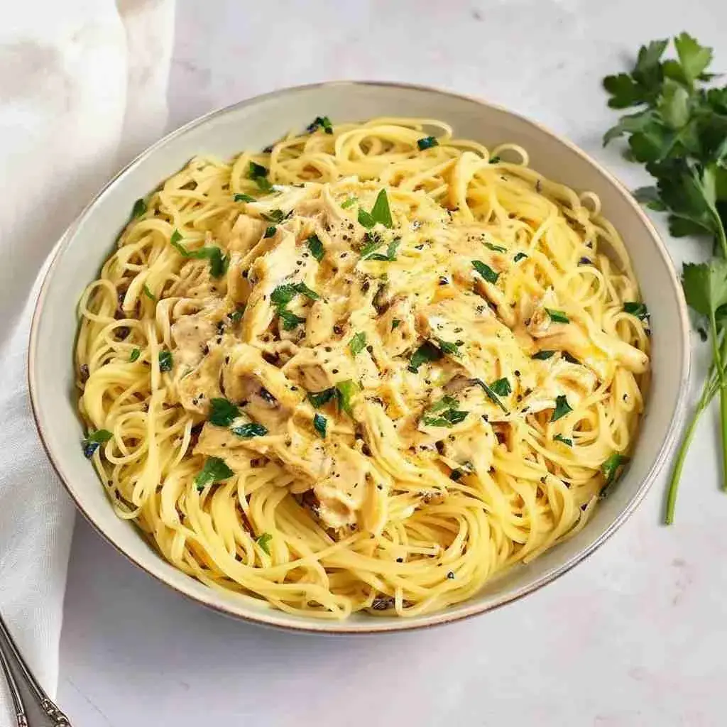 Crock Pot Angel Chicken 2 Crock pot angel chicken served over angel hair pasta on a white plate