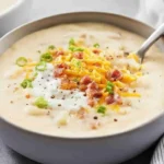 Bowl of loaded cheesy potato soup topped with bacon, cheese, and green onions
