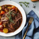 Juicy slow cooker pot roast with carrots, potatoes, and rich brown gravy.