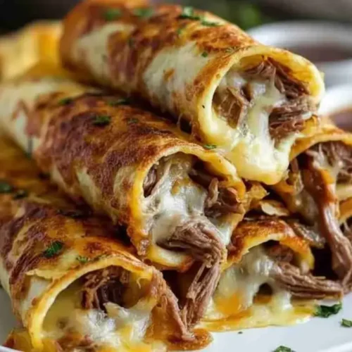 Crispy baked French dip tortilla roll ups on a platter with au jus