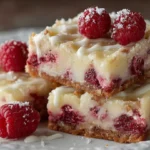 white chocolate raspberry bars cut into squares with raspberry swirl topping