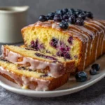 lemon blueberry loaf cake with glaze topped with fresh blueberries