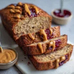 peanut butter and jelly banana bread loaf with peanut butter drizzle